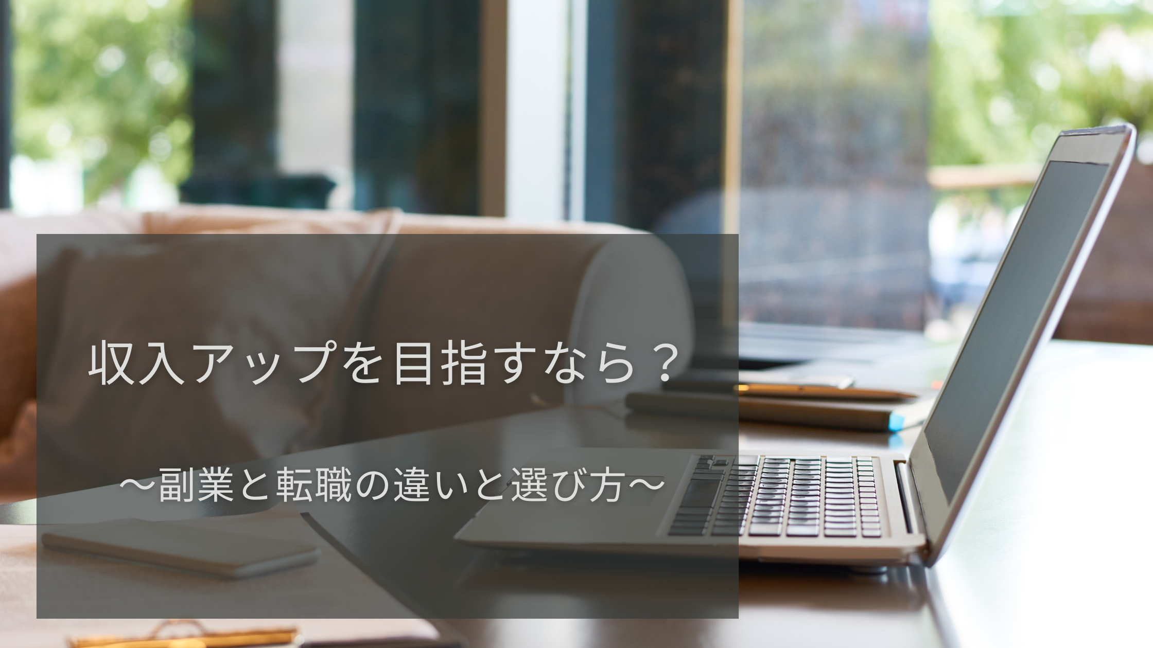 「カフェのような落ち着いた空間でノートパソコンを開く様子。画面中央には『収入アップを目指すなら？～副業と転職の違いと選び方～』というタイトルが半透明の黒い帯の中に白文字で表示されている。」